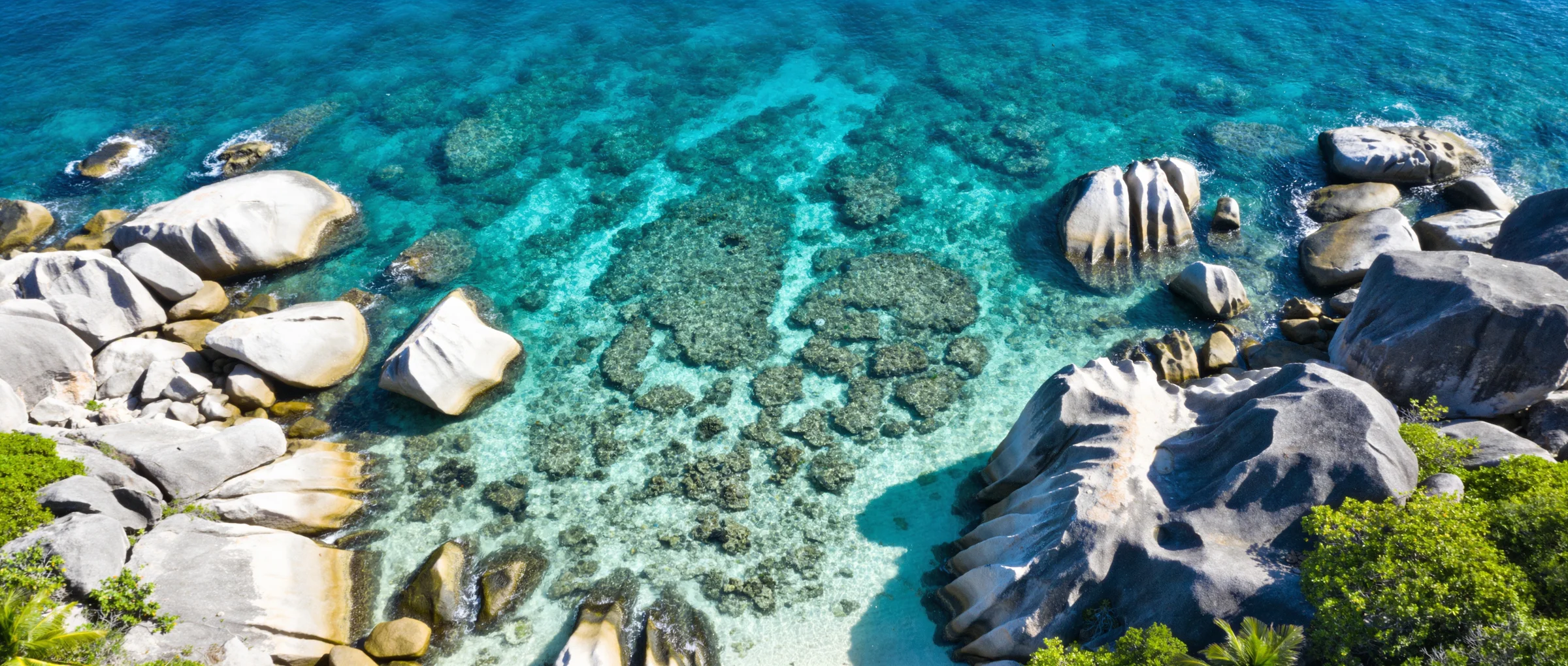 Aerial view of a sheltered turquoise cove among granite boulders